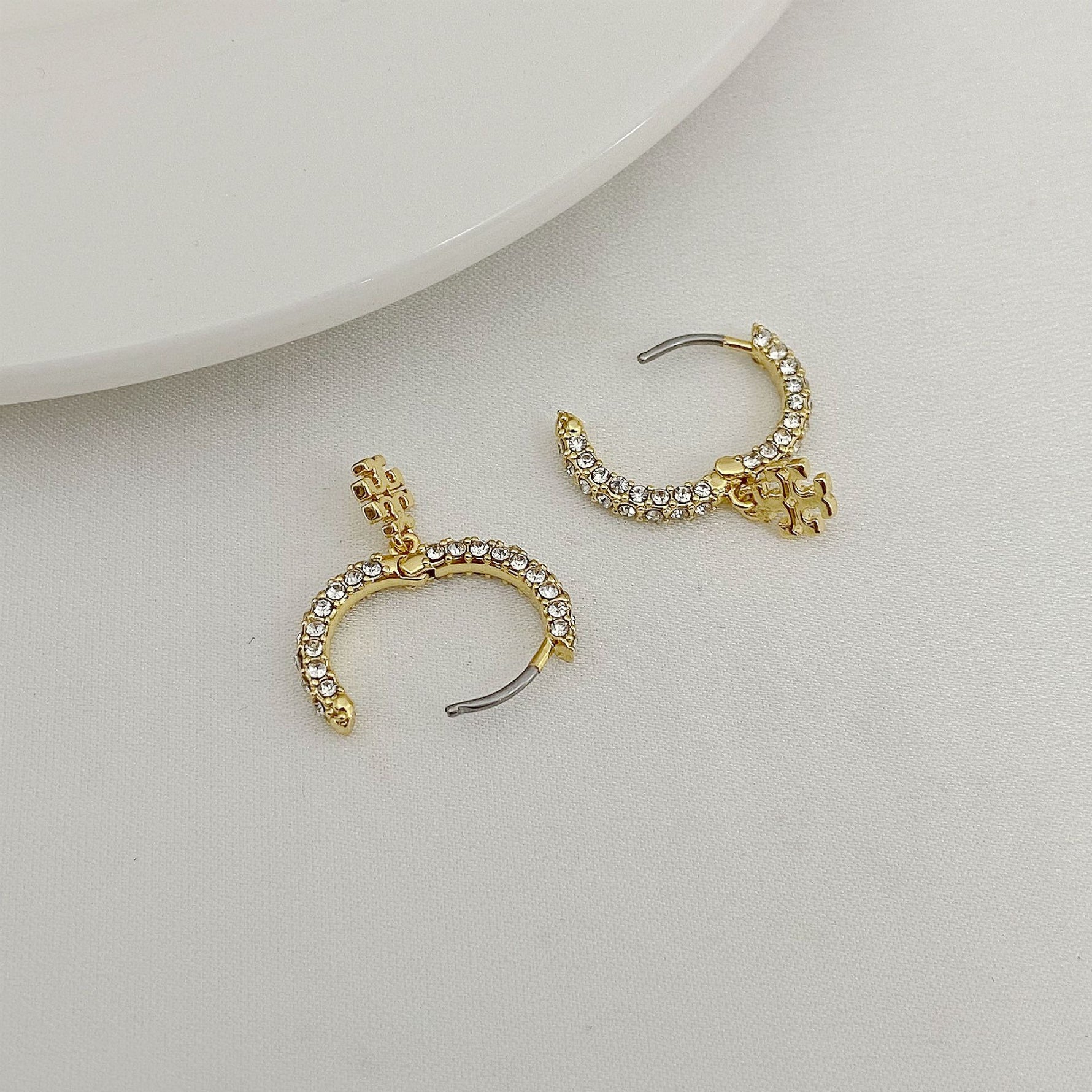 Gold-tone hoop earrings with rhinestone rim and charm, shown from side