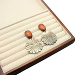 Flower-shaped mother-of-pearl stud earrings with brown dome posts and white petal rosette