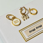 Three-piece enamel hoop earrings with white round charm and gold-tone metal hoops