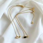 Gold-tone layered charm necklace with multiple thin chains and small heart pendants