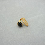 Asymmetrical gold open ring with black oval stone and translucent light centerpiece.