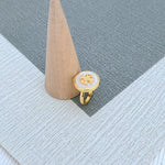 Round enamel metal ring with white shell center and gold-tone band