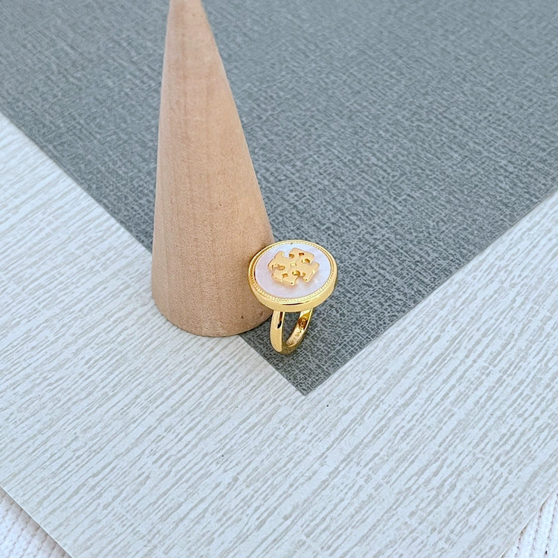 Round enamel metal ring with white shell center and gold-tone band