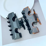 Two-tone shark T hair clip with black base and amber side highlights