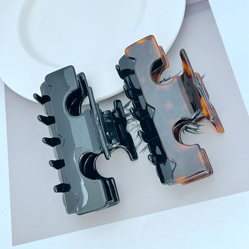 Two-tone shark T hair clip with black base and amber side highlights