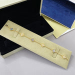 Goldfarbenes Kleeblatt-Armband mit weißlichen Blüten-Akzenten und funkelnden Zwischenstücken