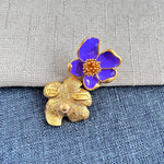Purple enamel floral stud earrings with gold-tone petals and golden beaded center