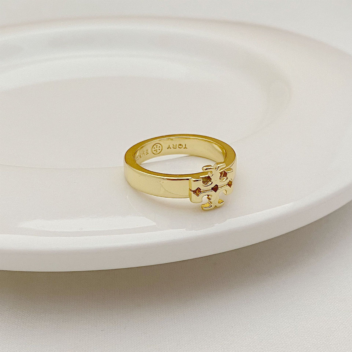 Gold-tone openwork ring with raised crest and engraved inner markings