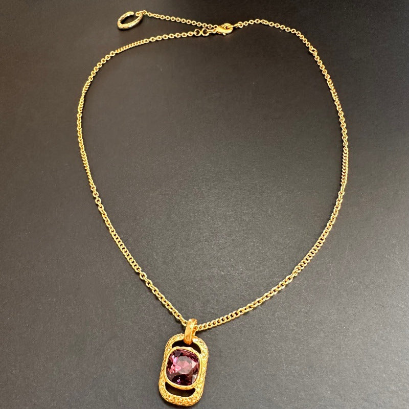 Gold-tone square pendant necklace with hammered texture and pink faceted stone