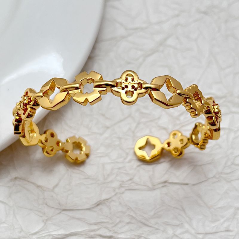 Gold tone four-leaf clover openwork bangle with central clover clasp and linked charms