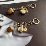 Gold squirrel and pinecone drop earrings with jeweled acorn-like tassels and dangle hoops