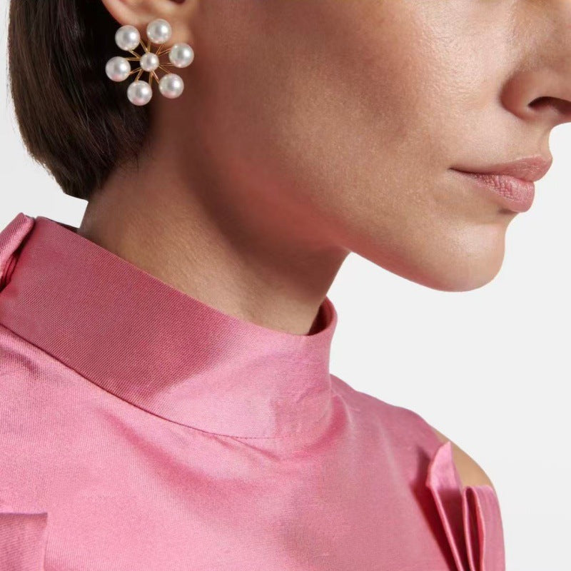 Pearl floral stud earrings with gold-tone ferris-wheel design on ear