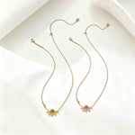 Gold-tone flower pendant necklace set with daisy charms and rhinestone centers