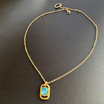 Gold-tone square pendant necklace with hammered texture and blue faceted stone