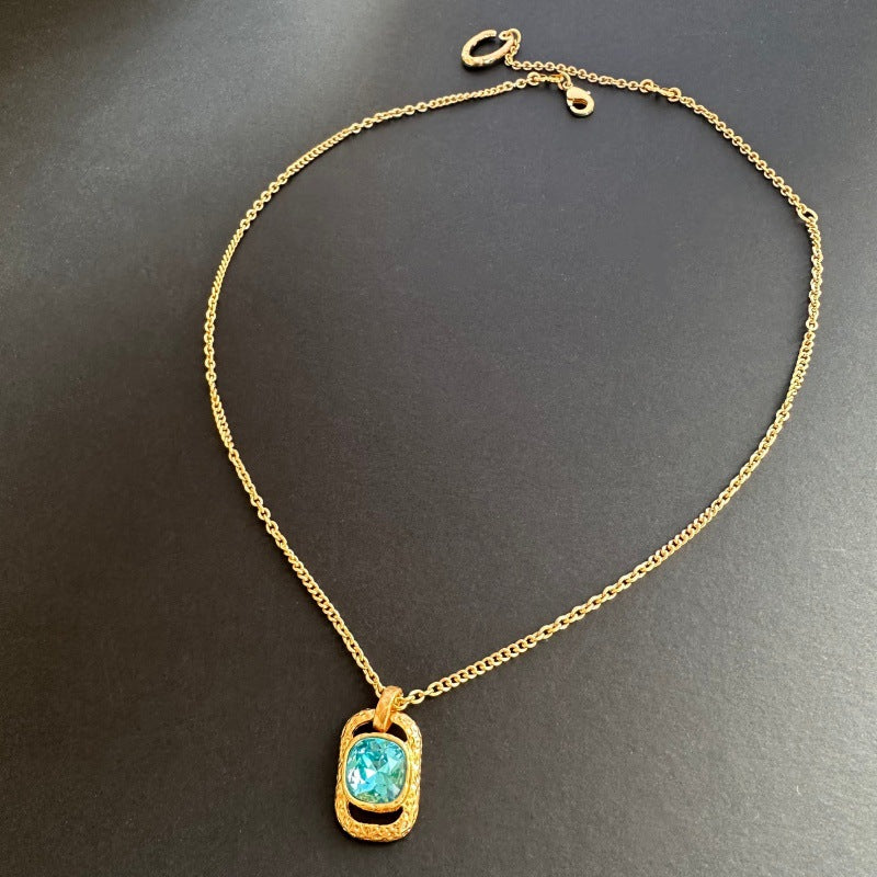 Gold-tone square pendant necklace with hammered texture and blue faceted stone