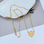 Gold minimalist openwork logo pendant necklace with round emblem and layered chain