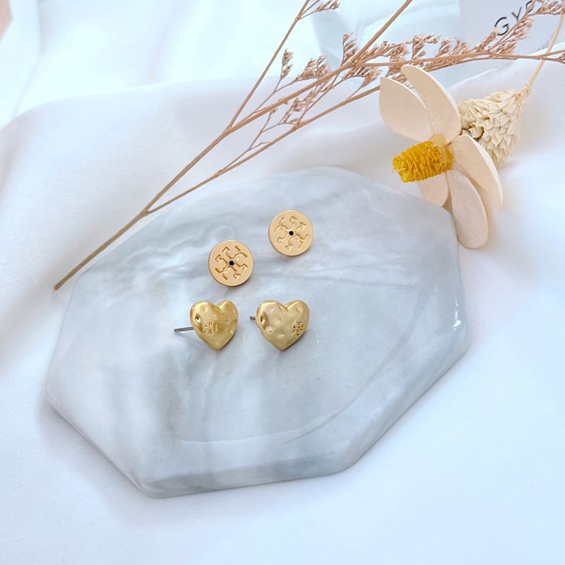 Gold heart-shaped matte metal stud earrings with small logo detail