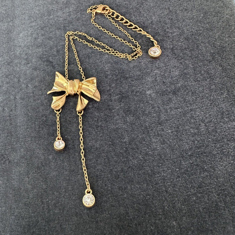Bow crystal tassel necklace, gold-tone with bow pendant and three round crystal drops
