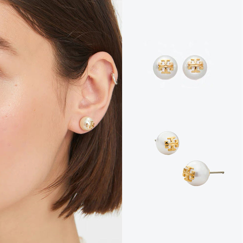 Round pearl stud earrings on a model: white pearls with gold geometric emblem