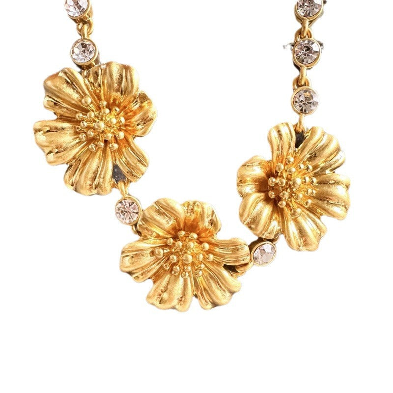 Gold-tone cherry blossom pendant necklace with sparkling clear rhinestone accents and chain links
