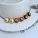 Round logo resin stud earrings, mixed burgundy and black resin centers with gold-tone trim