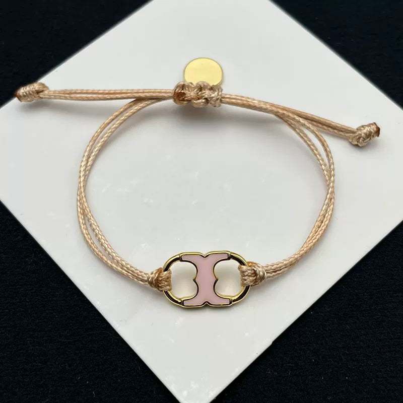 Pulsera ajustable con cordón marrón y dije esmaltado rosa con herrajes dorados