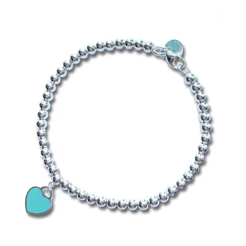 Silver bead bracelet with teal heart charm and small blue round charm