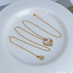 Gold-tone necklace with heart-shaped shell pendant and light enamel center detail