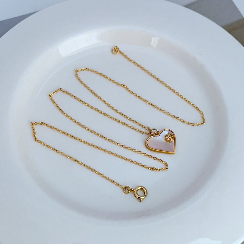 Gold-tone necklace with heart-shaped shell pendant and light enamel center detail
