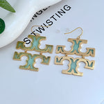 Teal-green logo drop earrings with gold-tone metal hooks
