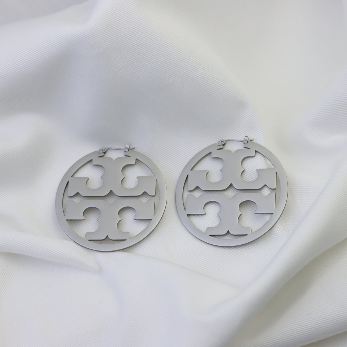 Matte silver round hoop earrings with cutout interlocking pattern