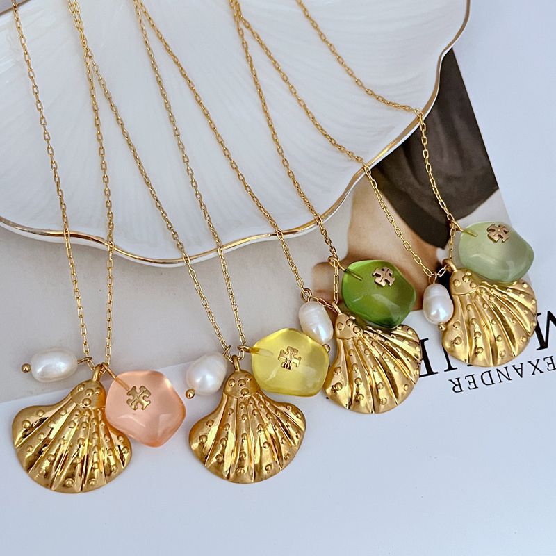 Gold-tone multi-charm shell pendant necklace with green and peach acrylic hearts, pearls