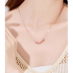 Rose-gold necklace chain with small pink charm accents and flower pendant