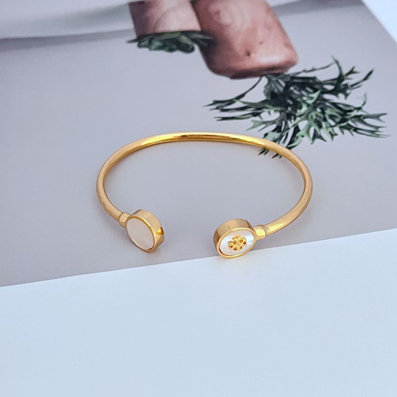 Gold-tone open bangle with round white enamel shell charms
