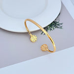 Gold-tone round logo open metal bangle with cutout discs on curved cuff.
