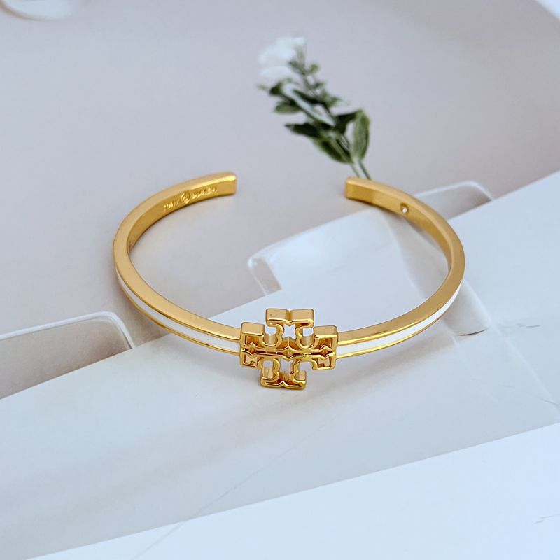 Gold-tone open metal bangle with enamel cutout logo centerpiece