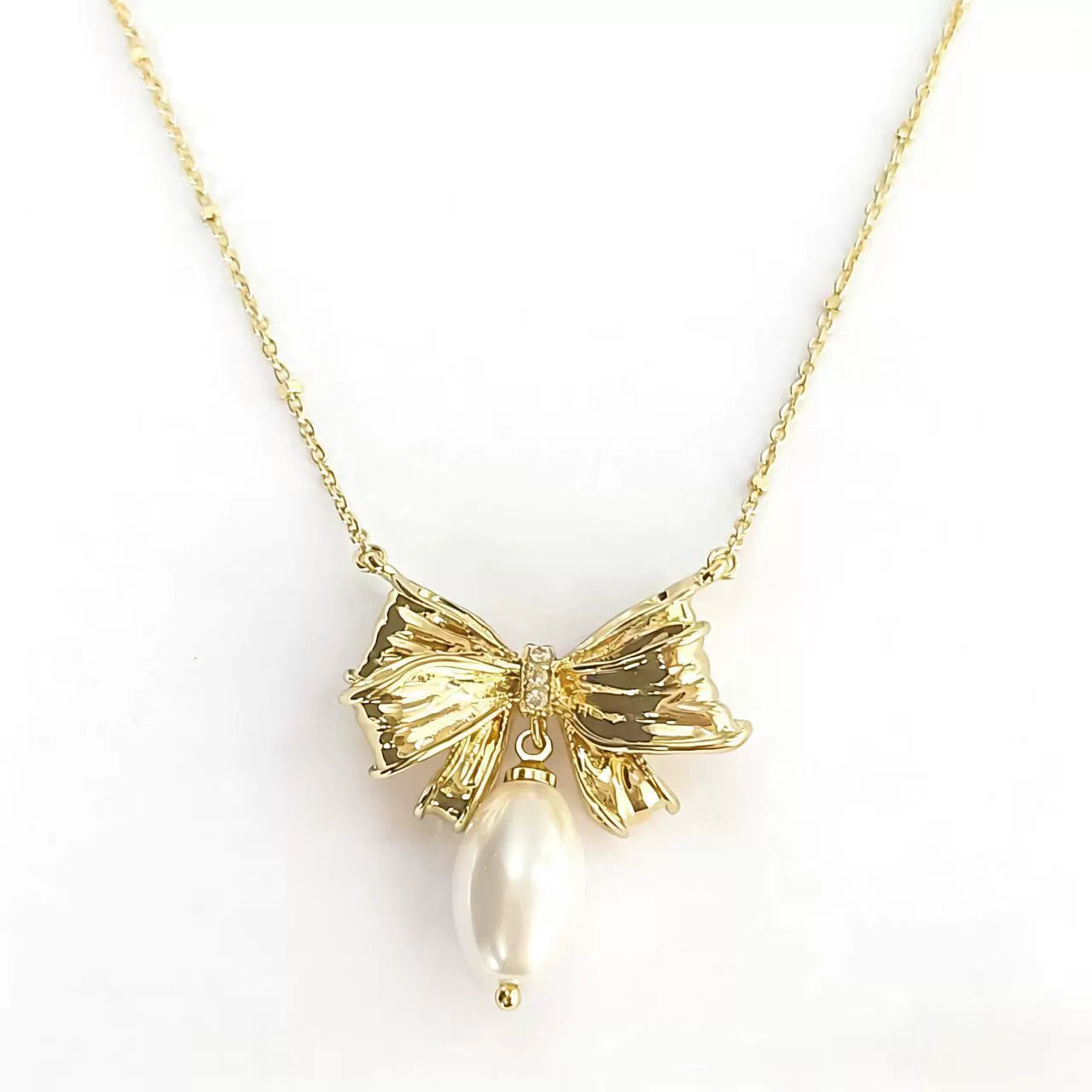 Gold-tone bow pendant necklace with white pearl drop and chain links