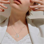 Silver heart pendant necklace with mother-and-child figures, gold bow detail on chain