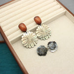 Flower-shaped mother-of-pearl stud earrings with wooden button posts, white and dark-gray pair