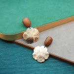 Flower-shaped mother-of-pearl stud earrings with brown dome backs and white petal design