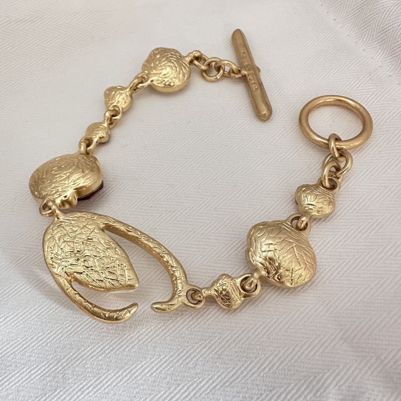 Gold tone bracelet with textured oval links and short bar clasp, no stones visible