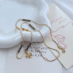 Gold-tone beaded charm necklace with yellow and black enamel stations