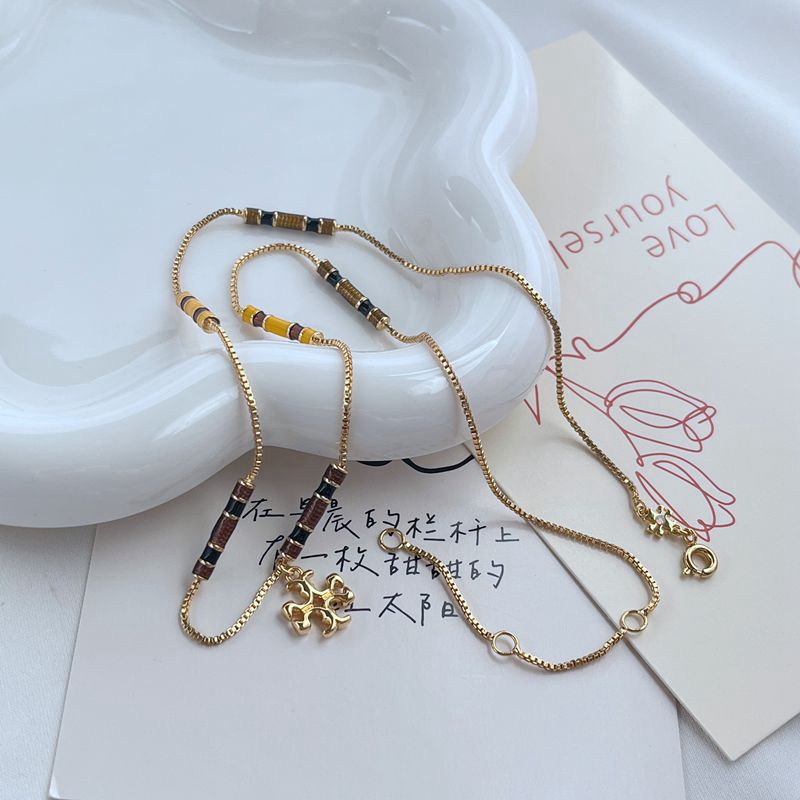 Gold tone beaded charm bracelets with black and white beads and clover pendants