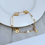 Tory Burch enamel agate logo bracelet in gold tone with white beads and puzzle charm