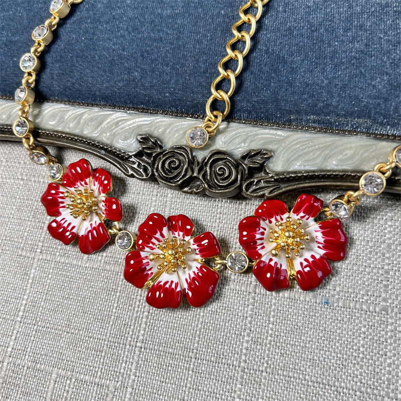 Close-up enamel cherry blossom pendant necklace with red flowers and gold filigree center