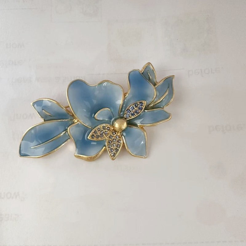 Light blue enamel jasmine flower brooch with gold outlines and crystal center