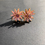 Enamel flower earrings in gold-tone with pink petals and pink center stones, stud style