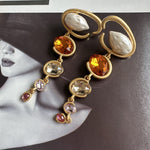 Long crystal drop earrings with gold rings and orange-yellow, champagne, and pink stones