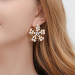 White pearl floral stud earrings with openwork petals and small pearl accents