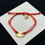 Red woven adjustable drawstring bracelet with gold clover charm and round coin tag